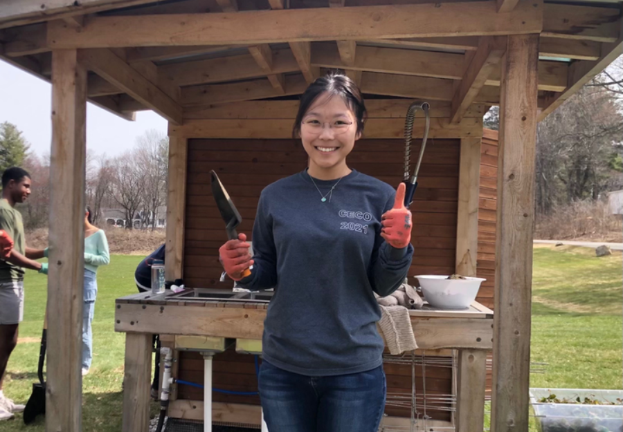 the author standing outside near garden holding gardening tools
