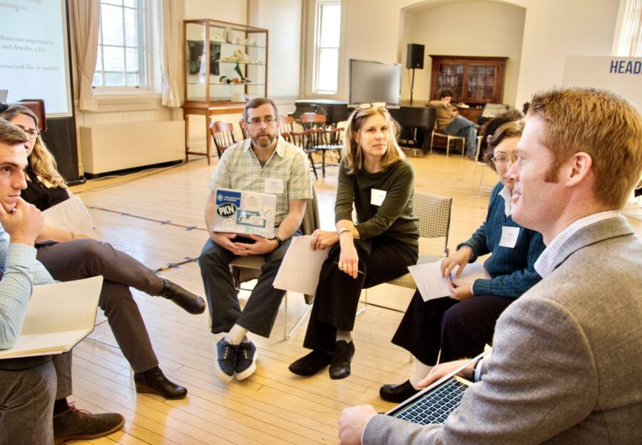 a group of people sit in a circle on chairs in a big, open room