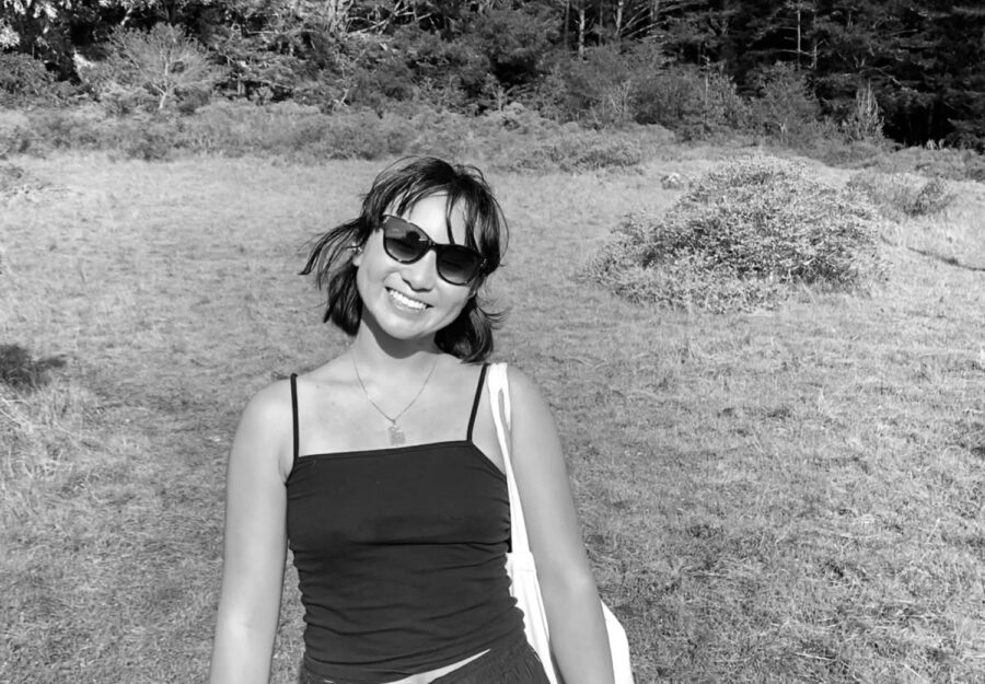 Katherine Wang ’21 stands in a field in summertime with a phone in her hand