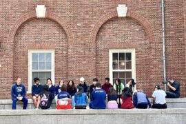 workshop students sitting on stoop by brick wall